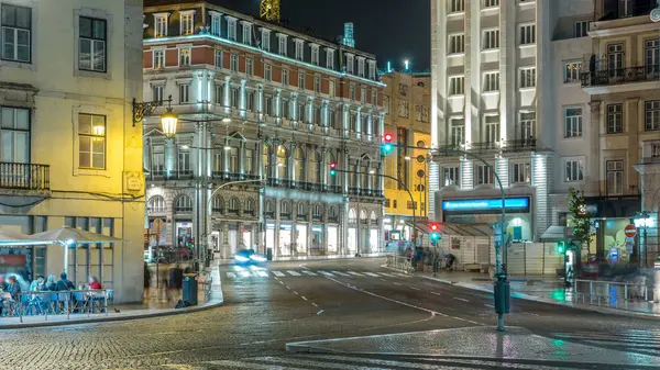 Dom Joao da Camara Square from Praca Dom Pedro IV or Rossio Square in Lisbon downtown night timelapse. Illuminated building and traffic on the road intersection