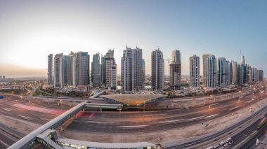 Dubai Marina 'dan Sheikh Zayed yoluna gece gündüz aydınlık gökdelenler ile hava panoramik görüntüsü, geçiş zamanı, Dubai. Trafik, köprüler ve metro istasyonu. Birleşik Arap Emirlikleri