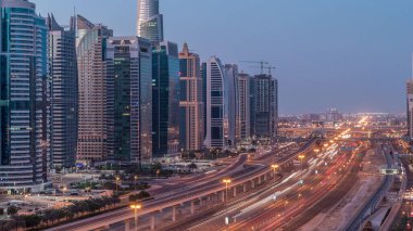 Dubai Marina 'dan Şeyh Zayed yoluna gece gündüz aydınlık gökdelenlerle geçiş zamanı, Dubai. Trafik, köprüler ve metro istasyonu. Birleşik Arap Emirlikleri
