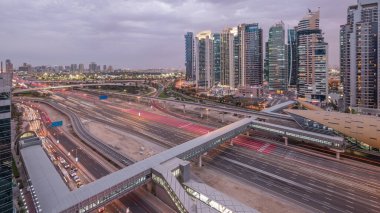 Dubai Marina ve Jlt gökdelenlerini, Dubai 'deki Şeyh Zayed yolunun hava görüntüsü gece gündüz geçiş zamanlarını çevreledi. Trafik, köprüler ve metro hattı. Birleşik Arap Emirlikleri