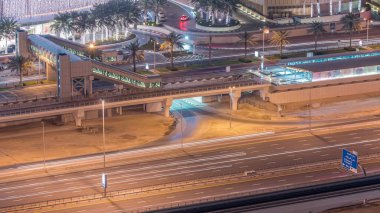 Dubai, Bae Dubai Marina gece timelapse tramvay durağıile alışveriş merkezi yakınında trafik havadan üst görünümü. Yanıp sönen ışıklar ve yolda trafik ile Aydınlatılmış modern kuleleri