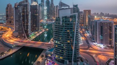 Dubai Marina yerleşim yerlerinin ve ofis gökdelenlerinin hava panoramik görüntüsü. Köprü ve rıhtımda gece gündüz trafik var. Gün doğumundan önce geçiş zamanı. Yüzen tekneler ve yatlar