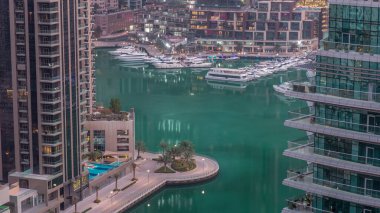 Dubai Marina 'daki rıhtım güvertesi gece gündüz geçiş zamanı. Kanalda yüzen tekne ve yatlar. Dubai, Birleşik Arap Emirlikleri