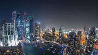 Dubai Marina gece geçiş timelapse havadan üst görünümü. Dubai, Bae yüzen yatlar ve tekneler ile gezinti ve kanal. Işıklı modern kuleler ve yolda trafik