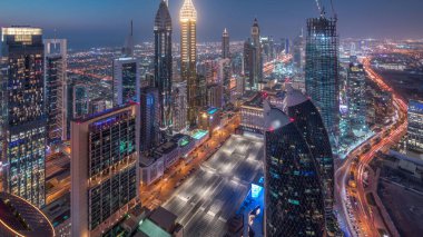 Sheikh Zayed Yolu yakınlarındaki binaların silueti ve Dubai, BAE 'deki hava gününden geceye geçiş. Günbatımından sonra finans merkezinde ve şehir merkezinde park yeri olan modern kuleler ve gökdelenler.