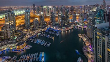 Dubai Marina gökdelenleri ve Jumeirah göl kuleleri Birleşik Arap Emirlikleri 'nde hava gününden geceye geçiş zamanlarını gösteriyor. Yolda trafik ve yüzen yatlar.