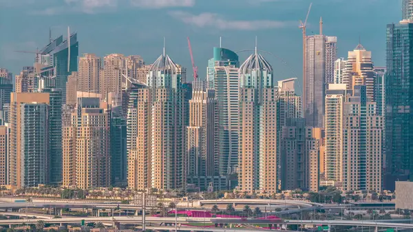 Dubai Marina gökdelenler ve golf sahası sabah timelapse, Dubai, Birleşik Arap Emirlikleri. Greens bölgesinden havadan görünüm. Yeşil çimve bulutlu gökyüzü. Otoyolda trafik