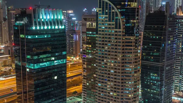 Jumeirah Lake Towers yerleşim bölgesi Dubai Marina yakınında hava gece timelapse. Işıklı modern gökdelenler ve yukarıdan trafik