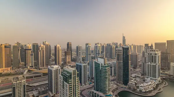 Dubai Marina ve Jlt akşam timelapse havadan üst görünümü. Dubai, Bae'de gün batımından önce yüzen yatlar ve tekneler lezne ve kanal. Modern kuleler ve yolda trafik
