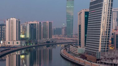 Gece gündüz kanal yakınlarındaki devasa gökdelenlerin hava görüntüsü Business Bay, Dubai, Birleşik Arap Emirlikleri 'ndeki geçiş zamanı..