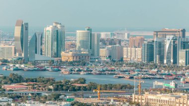 Güneşli bir günde, Deira, Dubai, Birleşik Arap Emirlikleri 'nde mavi gökyüzü bulunan ahşap gemilerle nehir kıyısında yeni modern gökdelenlerin hava manzarası.