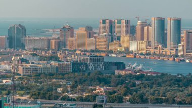 Çağdaş şehrin yeşil parkları ve büyük gökdelenler manzarası Dubai Creek, Dubai, Birleşik Arap Emirlikleri 'nde denizle kaplı.