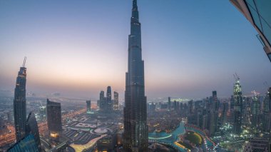 Şehir merkezindeki Dubai 'nin panoramik gökyüzü manzarası. Alışveriş merkezi, çeşmeler ve Burj Khalifa hava gece gündüz geçiş zamanı. Gündoğumundan önce modern gökdelenler ve bulutlu gökyüzü
