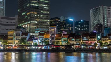 Singapur rıhtımında alışveriş merkezi restoranları ve yüksek gökdelenleri var Boat Quay 'in merkez iş bölgesinde gece hız sınırı üzerinde. Suya yansıyan evler