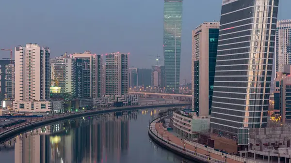 Gece gündüz kanal yakınlarındaki devasa gökdelenlerin hava görüntüsü Business Bay, Dubai, Birleşik Arap Emirlikleri 'ndeki geçiş zamanı..