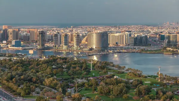 Güneş batarken Dubai Deresi ve Deira 'da arka planda deniz bulunan Park ve Mavi Nehir yakınlarındaki yeni modern binaların akşam manzarası Birleşik Arap Emirlikleri