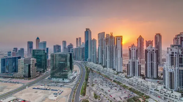 Günbatımında Business Bay, Dubai, Uae 'de bulunan birçok gökdelenle modern yerleşim ve ofis kompleksi. Körfez Bulvarı Parkı 'nın yanındaki büyük otoparkta arabalar ve trafik vardı.