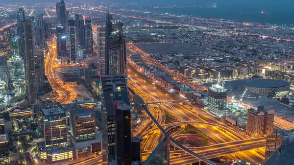 Dubai Şehir Merkezi gökdelenleri ve kavşağındaki trafiği gece gündüz gösteren fütüristik şehir manzarası. Gündoğumundan önce çatıdan modern kuleleri ve inşaatı olan sabah manzarası