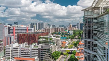 Singapur silueti Victoria caddesi ve Ulusal Kütüphane havadan zaman aralığı hipervanesi. Trafiği olan yeşil ağaçlar. Mavi gökyüzünde bulutlar