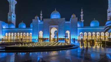 Şeyh Zayed 'in Ulu Camii gece saatlerinde aydınlandı. Aşırı hız, Abu Dabi, BAE. Çeşmeli ön manzara. Dünyanın en büyük üçüncü camii.
