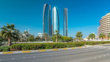 Ebu Dabi 'nin gökdelenleri Etihad Kuleleri' nin binaları zaman atlamalı. Avuç içleriyle ve trafiğiyle park et. Güneş cam yüzeyden yansıyor. Birleşik Arap Emirlikleri