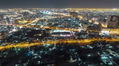Panorama, Ajman 'ın çatıdan yola çıkan trafiği gece vakti aydınlık binalarda ışıkları olan şehir manzarasını gösteriyor. Birleşik Arap Emirlikleri.