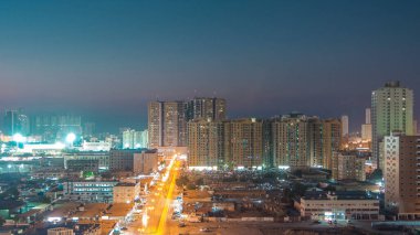 Ajman 'daki kuleleri olan şehir manzarası çatıdan gece saatine kuleleri ve büyük bir yolda trafiği olan. Birleşik Arap Emirlikleri 'nde gün batımından sonra aydınlanan binaların hava manzarası.