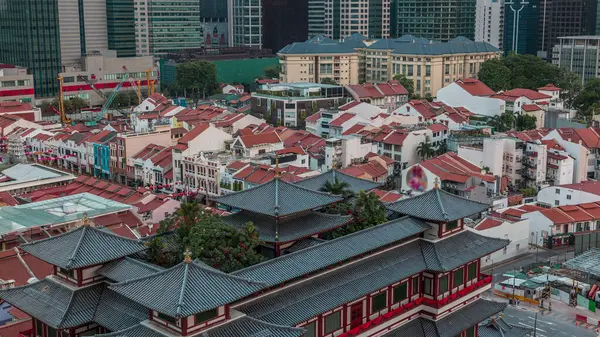 Singapur Çin Mahallesi 'ndeki Buddha Diş Anıtı Tapınağı. Arka planda şehrin silüeti var. Gökdelenleri ve kuleleri olan tapınak. Kırmızı çatılı eski evler