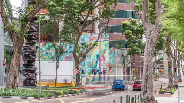 Battery Road Bulvarı 'nda trafik var ve Singapur' un şehir merkezinde yeşil ağaçlarla çevrili. Yeşil çimlerin yanında yürüyen insanlar