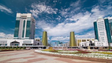 Nur-Sultan şehrinde Kazakistan Cumhuriyeti Senatosu 'nun inşa edilmesi. Ön planda çiçek açmış. Arka planda Nurzhol Bulvarı. Yazın mavi bulutlu gökyüzü