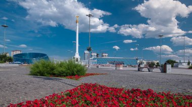 Yıldız heykeli Kazak Eli 'ın kuş Samruk ve Bağımsızlık Sarayı' nın zaman atlaması ve kırmızı çiçek tarhı ön planda. Nur-Sultan şehri, Kazakistan