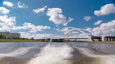 Astana, Kazakistan. Keyif teknesinden Astana 'da Ishim nehrinde hareketli bir seyahat görüntüsü. Mavi gökyüzü ve bulutlarla dolu bir yaz gününde. Bulanık hareket