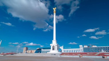 Kazakistan 'ın başkenti Astana' daki Independence Meydanı 'ndaki Kazak Eli Anıtı' nın zaman atlaması görüntüsü. Alttaki çiçek tarhında. Yaz günü mavi bulutlu bir gökyüzü. Nur-Sultan şehri