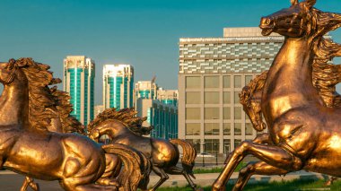 Atların heykelleri, Astana Opera Tiyatrosu 'nun önündeki yeşil çimlerde gün batımında, Kazakistan' da aşırı hızlanırlar. Nur-Sultan şehri