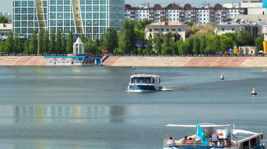 Astana, Kazakistan. Astana 'da Ishim nehrinde hareketli bir eğlence teknesi var. Yazın mavi gökyüzü ve bulutlarla