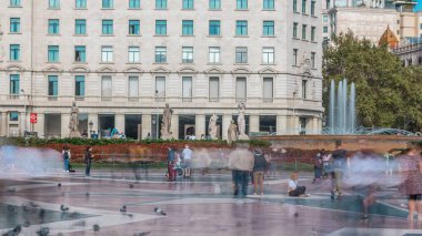 Barcelona 'nın Kalbinde Yaşam: Placa de Catalunya' nın Zaman Çizelgesi, Bustling Şehir Merkezi. Büyüleyici Çeşme ve Çiçek Yatağı 'nın ortasındaki insanlar bu Merkez Meydanı' nın canlılığını yakalıyorlar.