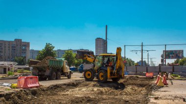Endüstriyel kazıcı toprak kazıyor ve bir yol inşaatında bir kamyon zaman tüneline yüklüyor. Büyük bir şehirde tramvay raylarının yeniden inşasına hazırlık
