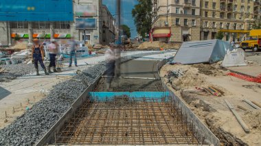 Beton dökme, yol inşaatının takviye edilmesi için çalışıyor. Üniformalı ve beton pompa makineli bir sürü işçi var. Tramvay raylarının yeniden inşası