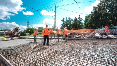 Tramvay rayları onarılan ve bakım süreleri yüksek olan yol inşaatı. Metal bir şebekede mikserden beton dökülüyor. Kavşağın ortası..