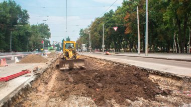 Tramvay rayları onarımı ve bakımı olan bir yol inşaatı. İnşaat alanında çalışan endüstriyel makineler zaman ayarlı. Buldozer yerde çalışıyor.