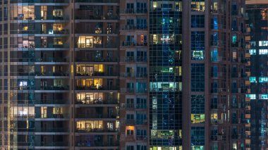 Çok öykülü modern cam konut içinde parlayan pencere eşiği ışık gece timelapse bina. Daireler insanlar. Evler de akşam aydınlatılmış. Dubai Marina, Birleşik Arap Emirlikleri.