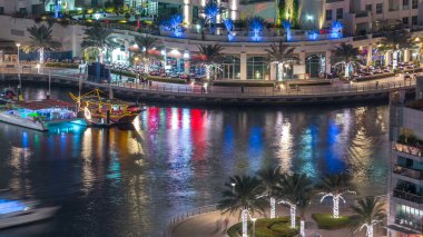 Lüks Dubai Yat Limanı kanal geçen tekneler ile ve mesire Restoran gece timelapse ile üst görüntülemek üzerinden yukarıda ile ışıklandırılmış gökdelenler. Dubai, Birleşik Arap Emirlikleri