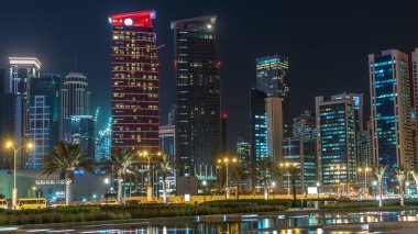Geceleri Doha 'nın ufuk çizgisi. Yıldızlı gökyüzü Park Timelapse, Katar' dan görülüyor. Aydınlatılmış gökdelenler ve kuleler çeşme suyuna yansıyor