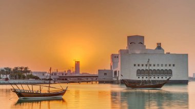 Katar 'ın Doha kentindeki İslam Sanatları Müzesi yakınlarındaki günbatımında, arkasında yükselen gökdelenler görülüyor. Öndeki eski tekneler.