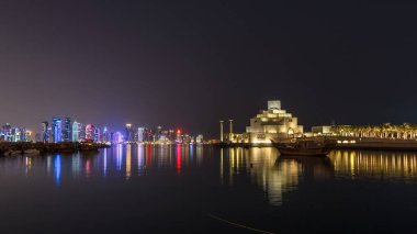 Katar 'ın Doha kentindeki eski dhow liman gecesi hiperhızının panoramik bir görüntüsü. Arka planda West Bay silueti var. Arka planda modern gökdelenler ve müzeler ve ön planda eski tekneler