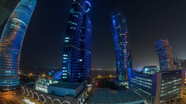 Katar 'ın Doha Zaman Çizelgesi' nde Batı Körfezi bölgesinin ufuk çizgisi. Aydınlatılmış modern gökdelenler geceleri çatıdan gökyüzü manzarası. Arka plandaki körfez ve yoldaki trafik