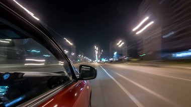Hızlı sürüş yapan bir şehrin gece caddesinde, yüksek hızda ışık yansıtan bir yolda, hızlı sürüş yapan bir arabadan saçma sapan bir şehir görüntüsü. Modern bir şehrin hızlı ritmi. Bulanık hareket