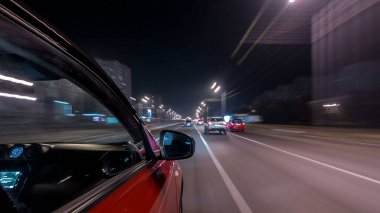 Hızlı sürüş yapan bir şehrin gece caddesinde, yüksek hızda ışık yansıtan bir yolda, hızlı sürüş yapan bir arabadan saçma sapan bir şehir görüntüsü. Modern bir şehrin hızlı ritmi. Bulanık hareket