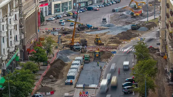 Turnalar ve kazıcılar şehir sokaklarındaki madenlerde toprak hareketliliği üzerinde çalışıyorlar. Kamyona yükleniyor. Yol inşaatında kazı sırasında ağır inşaat ekipmanları