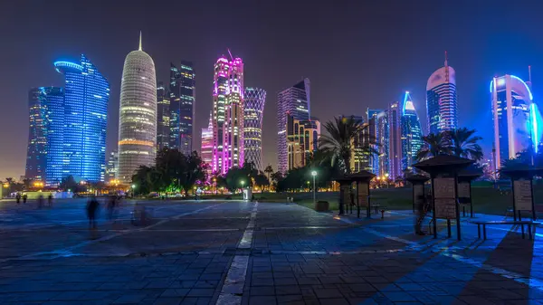 Doha 'nın yüksek katlı mahallesinde gece vakti hızlandırılmış hipervane, parktan görülmüş. Batı körfezinde aydınlatılmış gökdelenler ve palmiyeler